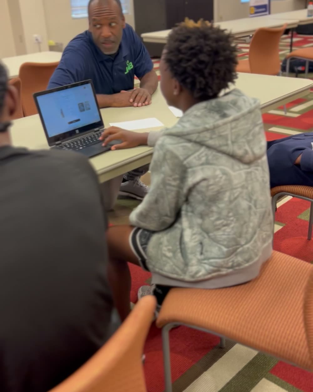 Walt Jordan sitting across the table coaching a student working on a laptop