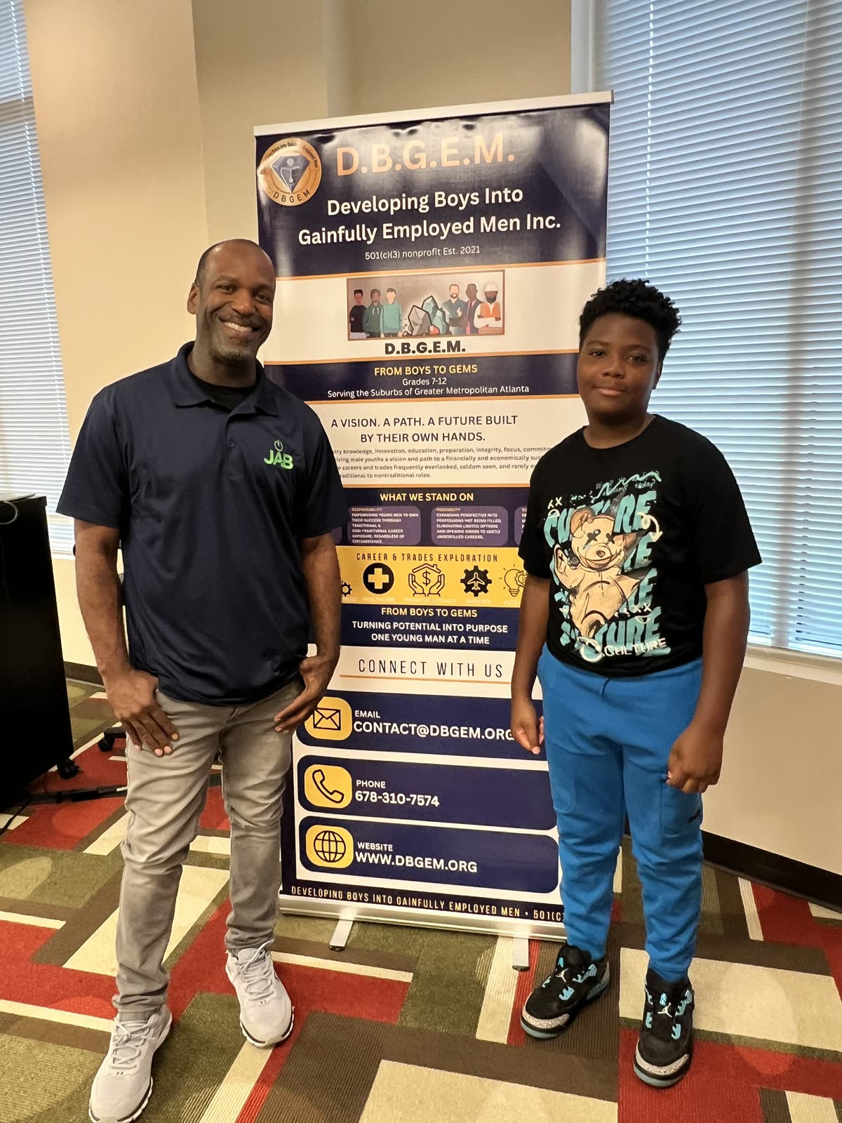 Walt Jordan with a student in front of the D.B.G.E.M. banner at the summer camp
